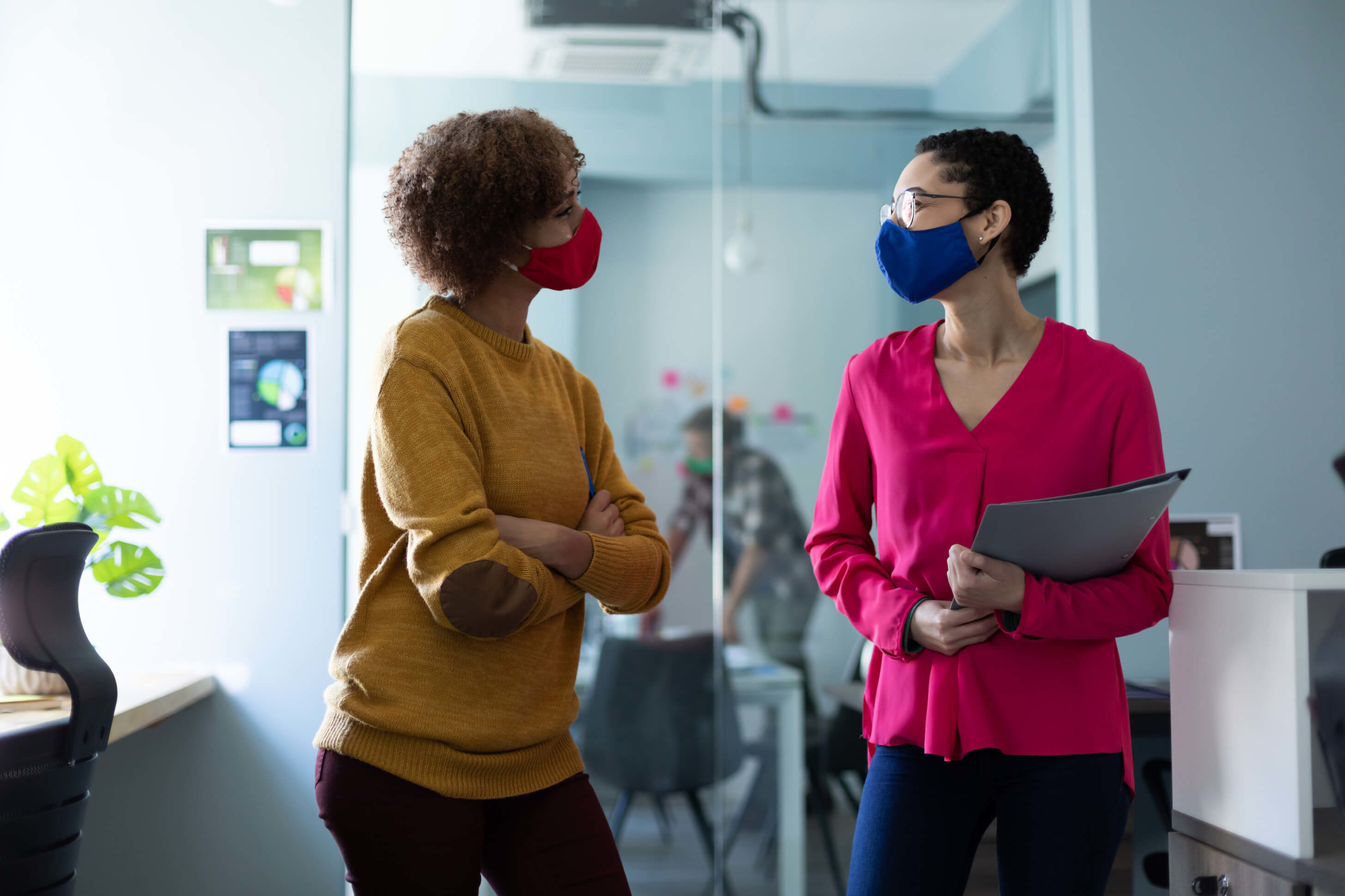 Two women in masks in business workplace